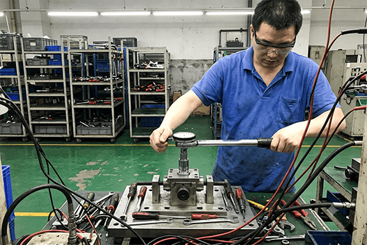 A quality control inspector using a torque wrench to test a tool on a factory line.