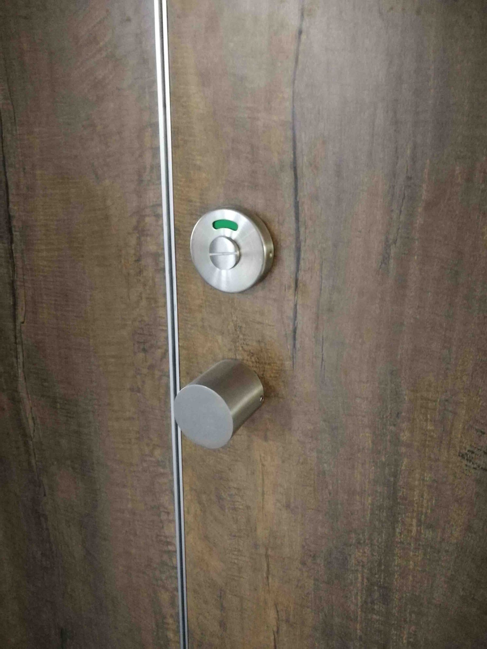 A close-up shot of a modern, heavy-duty 304 stainless steel indicator lock installed on a commercial restroom stall door.