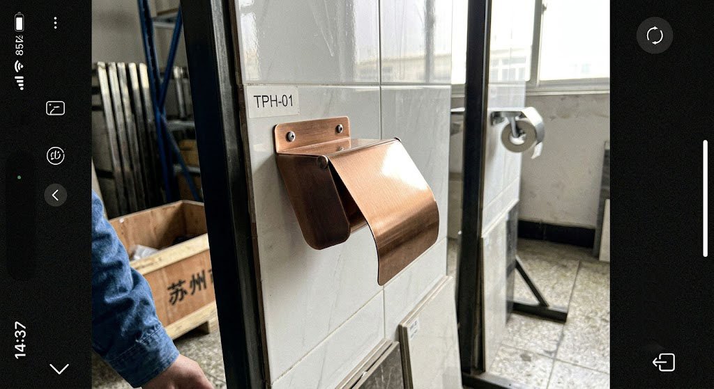 A pristine brushed copper toilet paper holder in a sleek, minimalist hotel bathroom, looking clean and free of smudges.