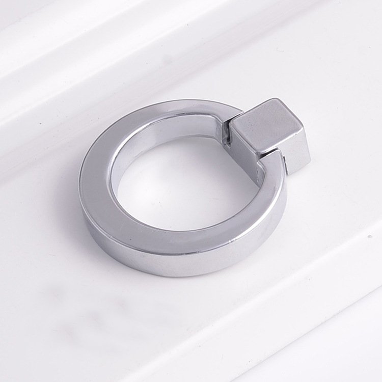 A close-up view of a black aluminum edge pull installed on a white drawer, showing its low profile and seamless integration.