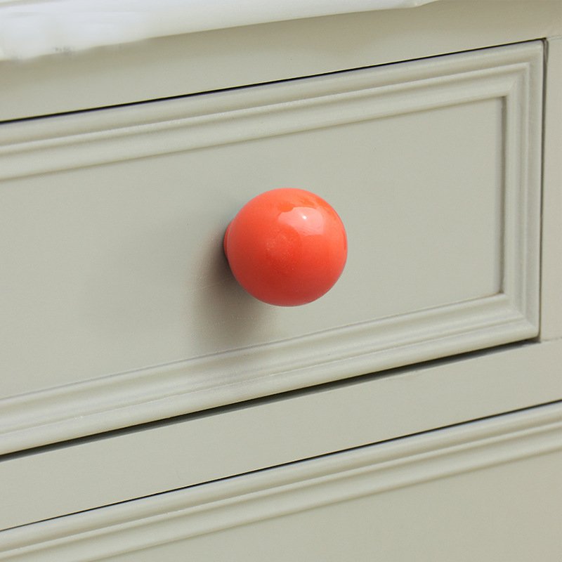 Dresser with Mixed Pastel Knobs A white nursery dresser featuring an assortment of different colored pastel knobs on its drawers.